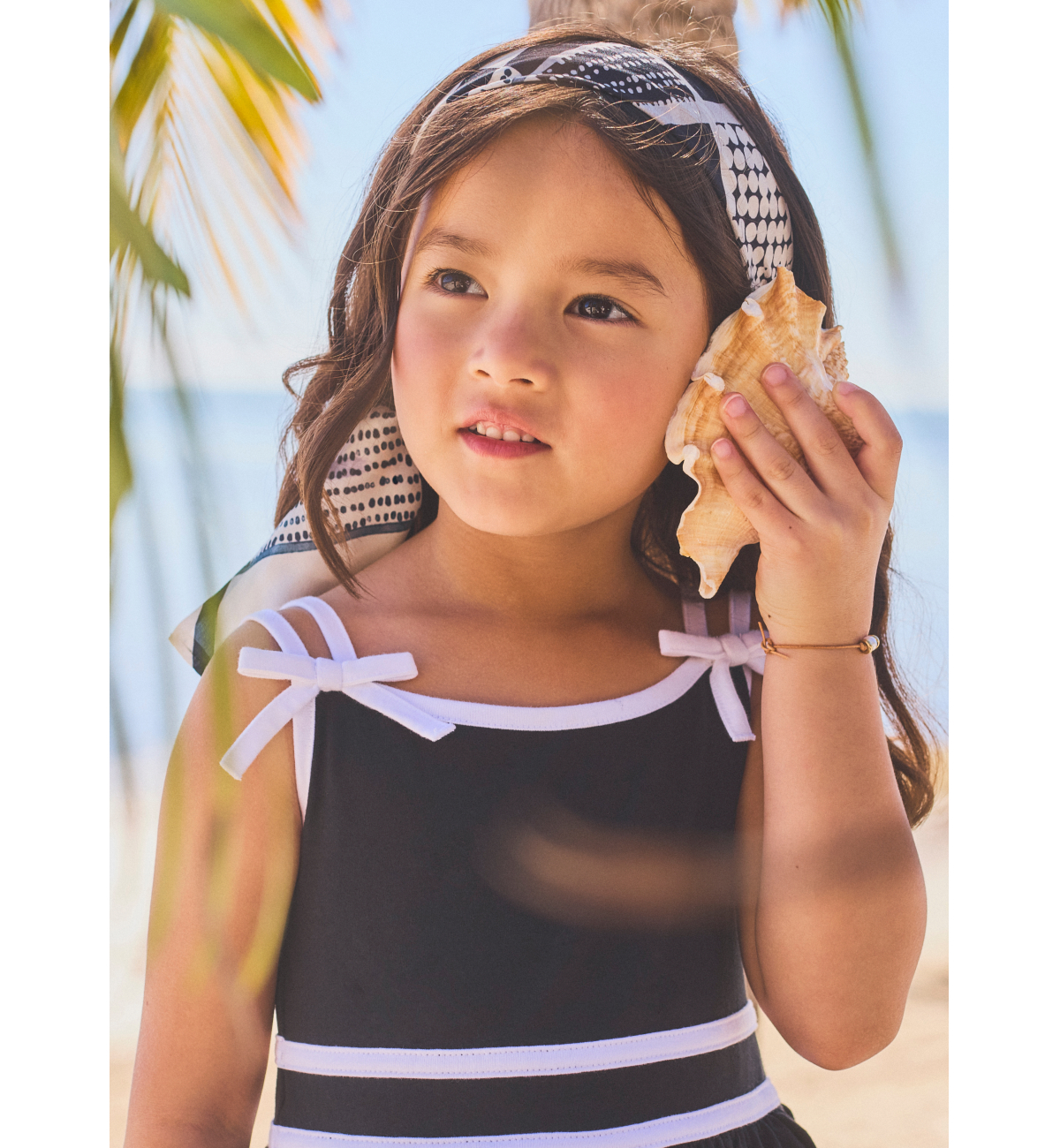 Young girl holding seashell to ear on beach