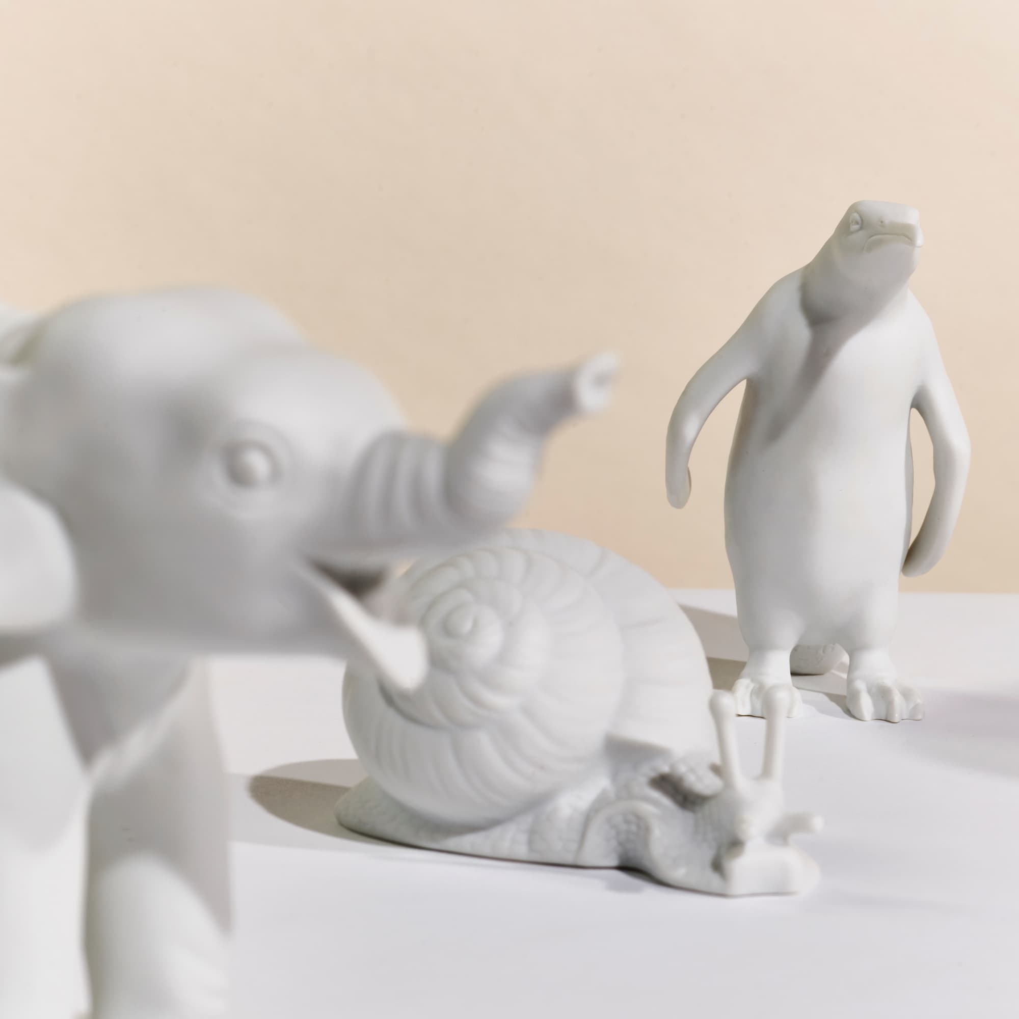 Weiße Porzellanfiguren: Schnecke, Elefant und Pinguin 