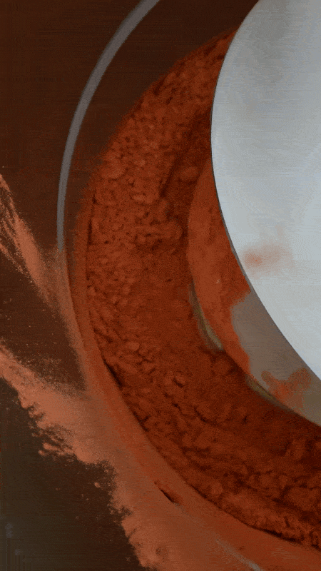 Red freeze-dried fruit powder being churned into creamed honey