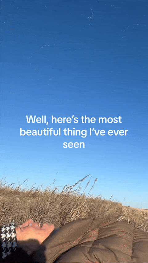 an image of a person laying on a field with a sky background