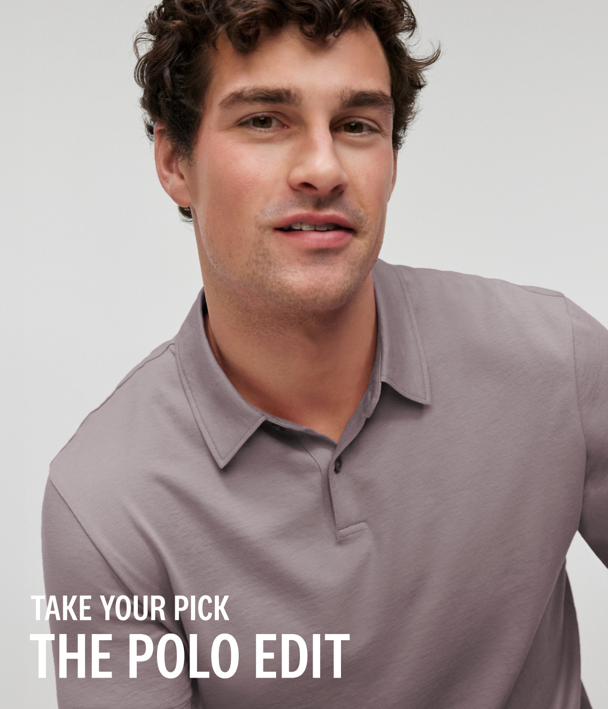 Close-up of a model wearing a Pima T-Shirt Polo in Zinc white white overlay text in the bottom left corner reads, "TAKE YOUR PICK / THE POLO EDIT."
