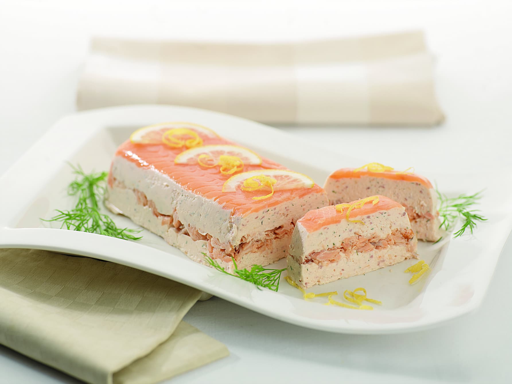 Sliced smoked salmon terrine on a platter with lemon and dill