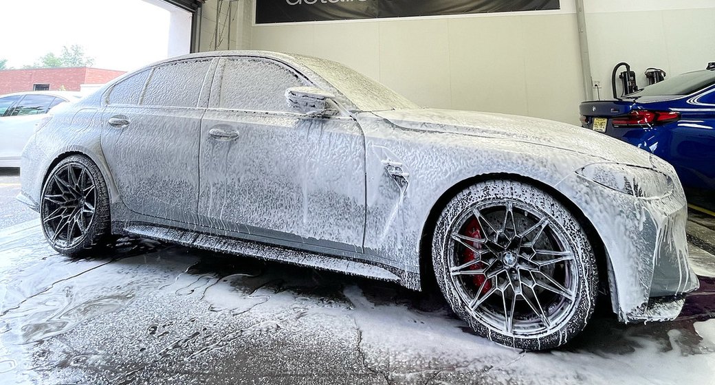 Gray BMW M3 covered in foam during a wash inside the Detailer's Domain shop