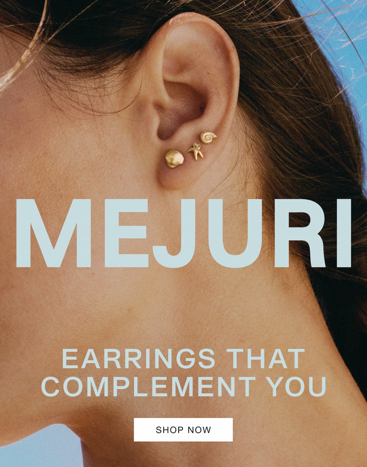 Close-up of a woman's ear wearing small Mejuri gold studs against a bright blue sky — Mejuri, Earrings That Complement You.