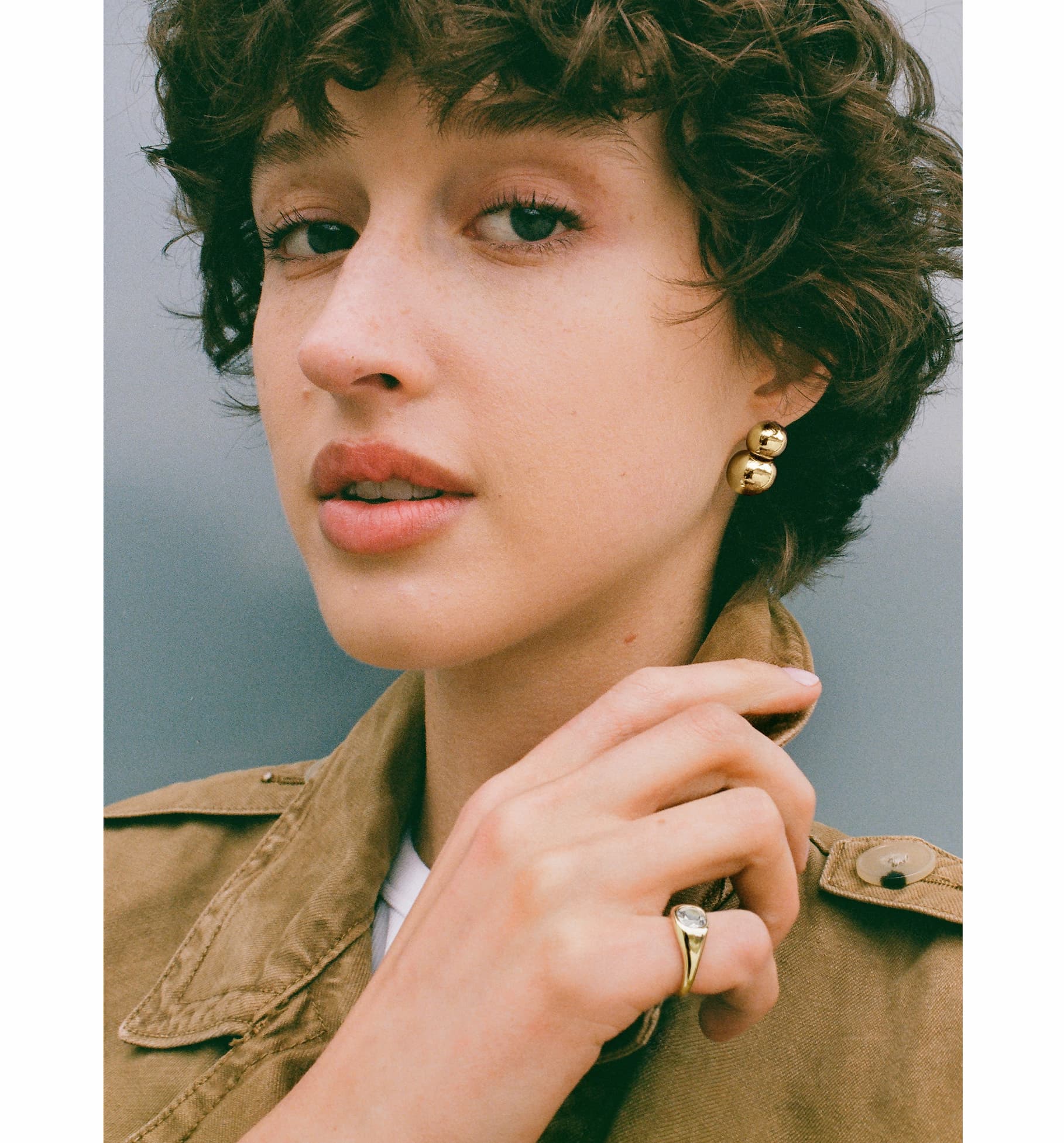 Woman wearing Mejuri Gia Drop earrings and a gold signet ring.