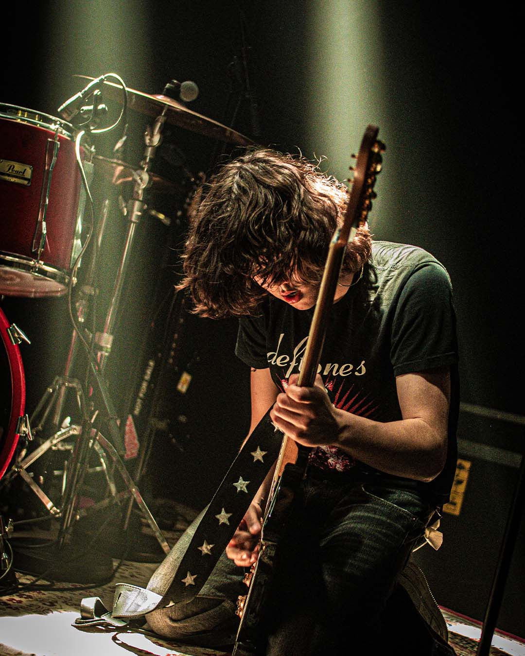 an image of a man playing a guitar on stage with a drum