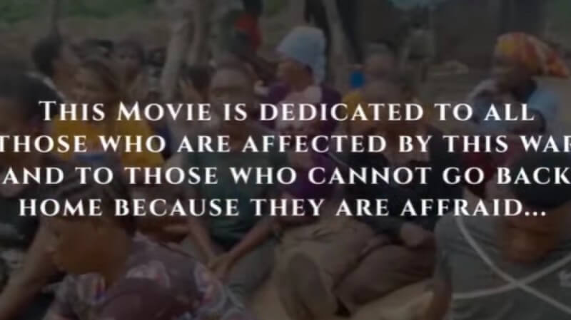 A still from a video. There is a group of people, and overlaid are the words "This movie is dedicated to all those who are affected by this war and to those who cannot go back home because they are afraid"