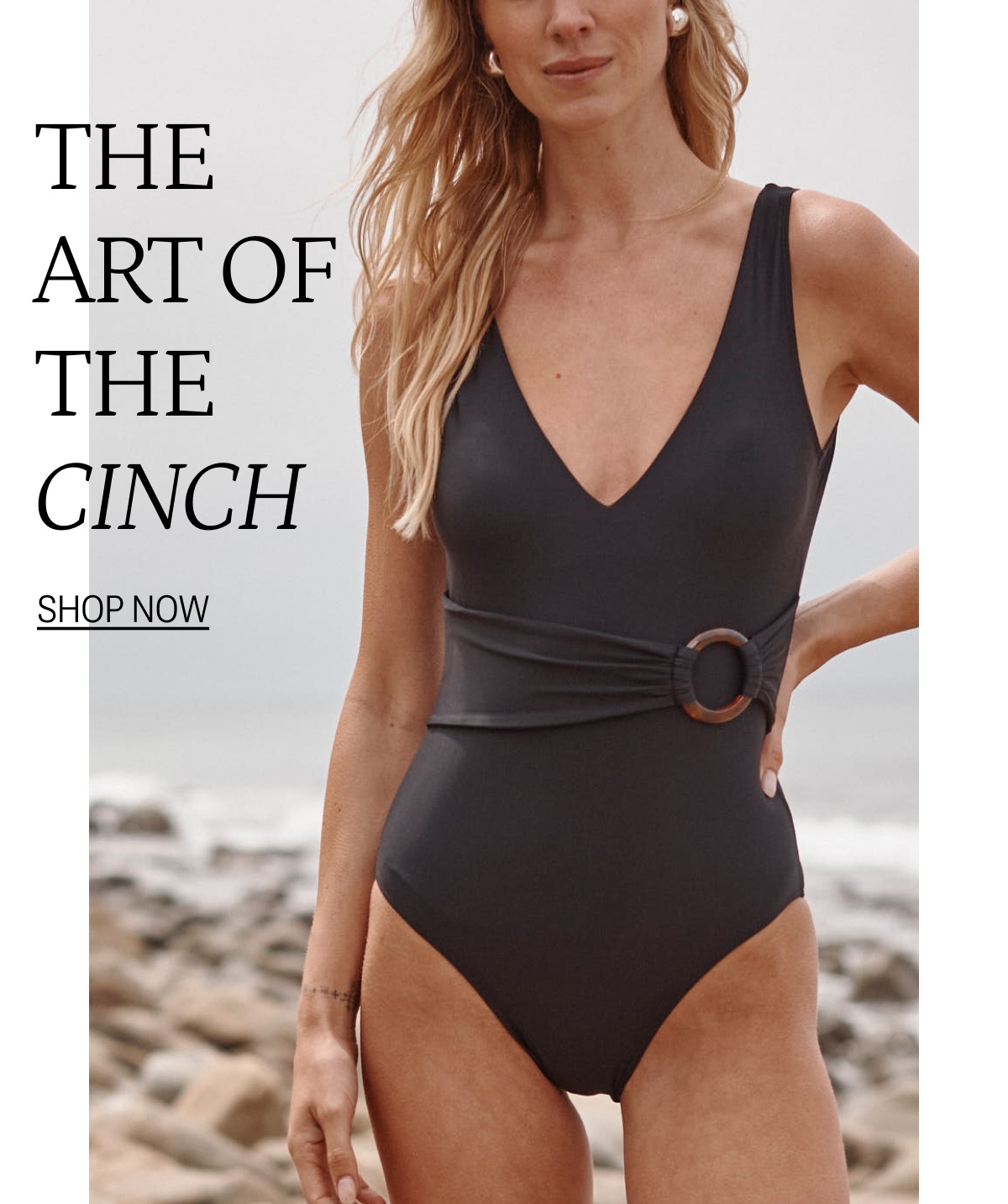 Model in black cinch belted one piece swimsuit