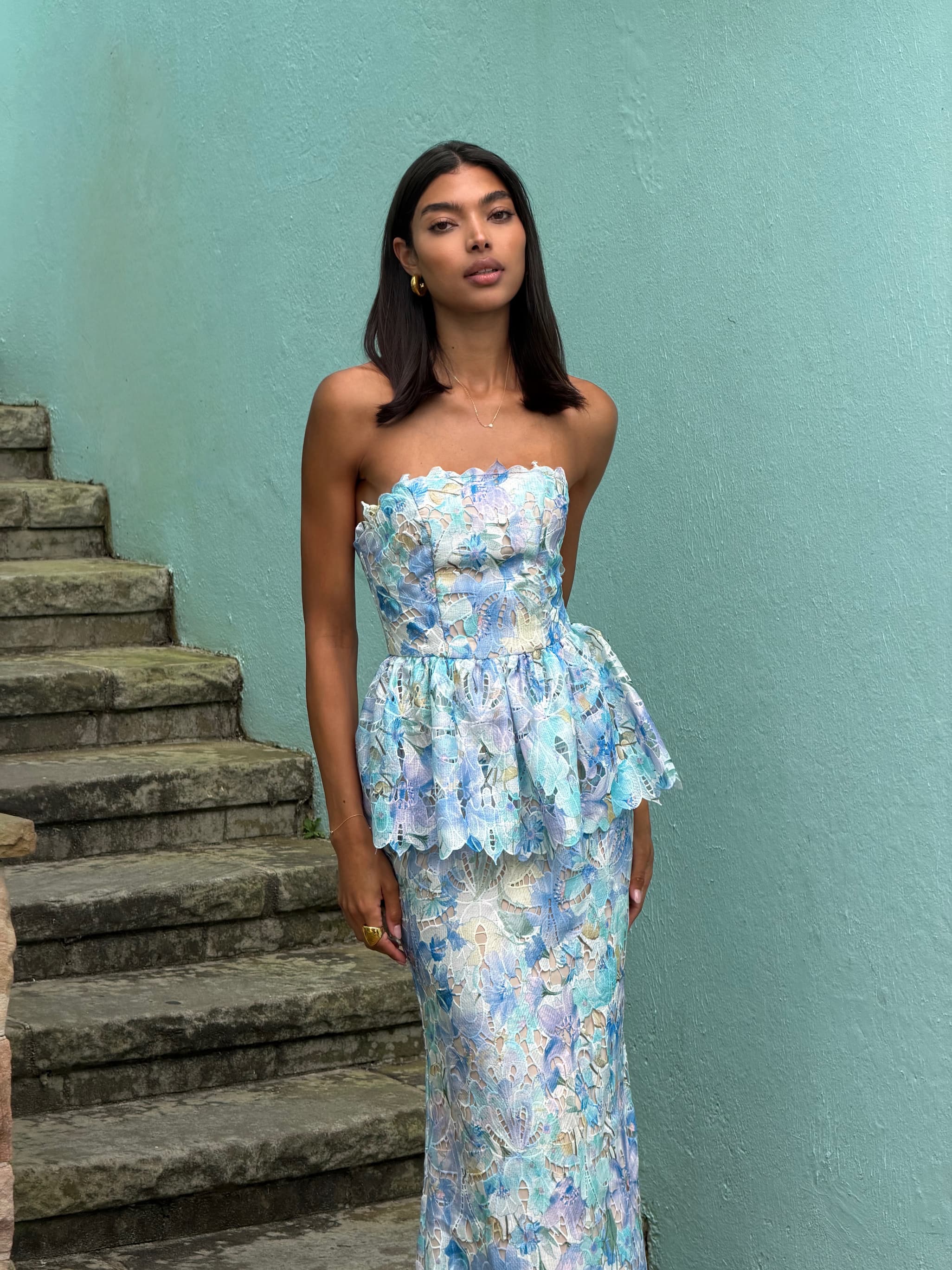 an image of a woman in a dress standing by a pillar