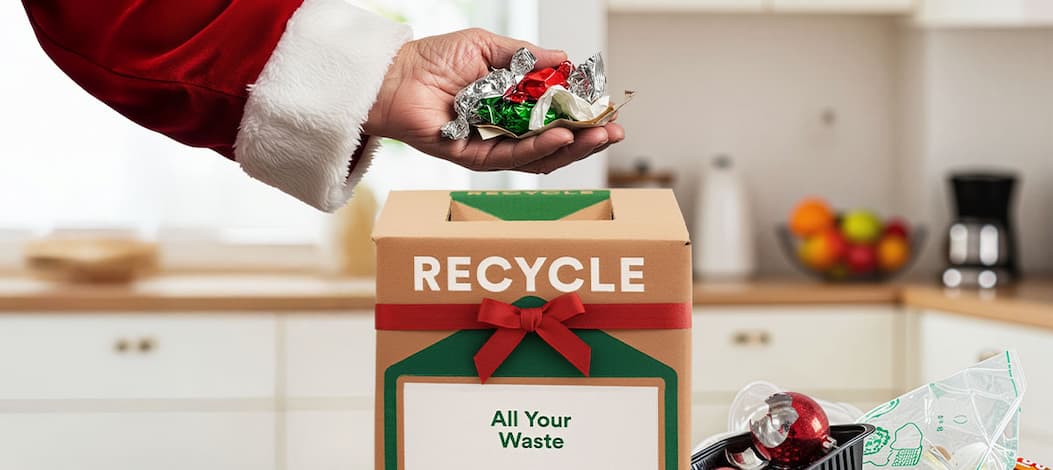 Santa's hand displayed throwing festive waste in recycling box