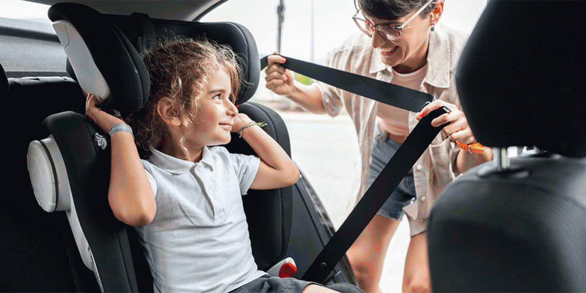 Child being strapped into car seat, and two children crossing a school crosswalk
