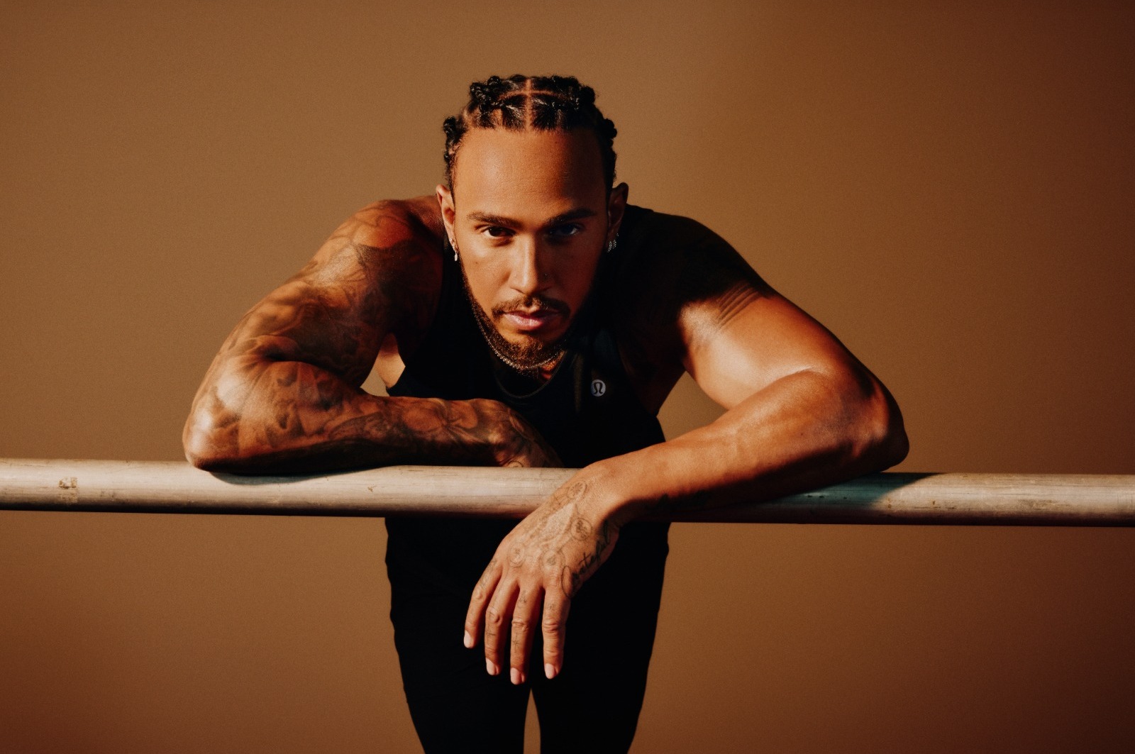 Lewis Hamilton leaning against a barre, wearing his Lululemon workout clothing