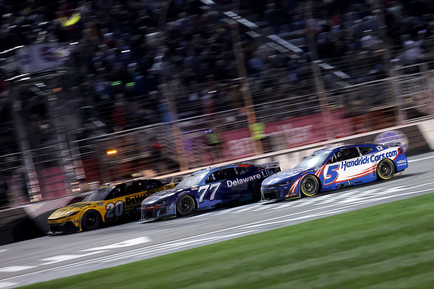 The yellow flag waving across the start/finish line as Christopher Bell, Carson Hocevar, and Kyle Larson cross at Atlanta