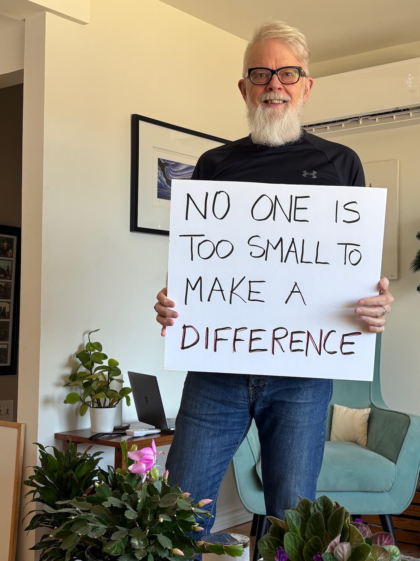 David Hayward holding up a hand-drawn poster that says, "No one is too small to make a difference."