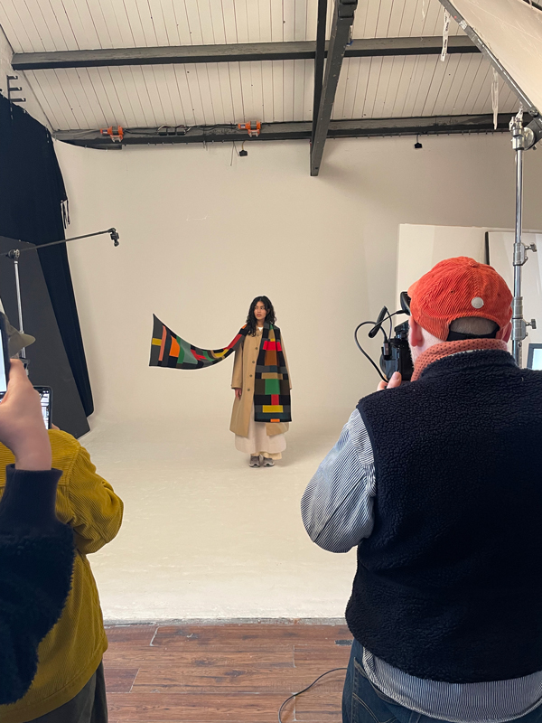 in this behind the scenes photo you can see the apparatus used to hold the end of the scarf as if blowing away while the model is photographed by Huw Morgan