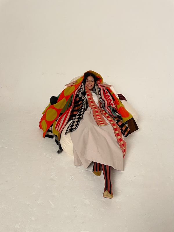 model lies on the floor of the studio smiling under a pile of Jo Gordon scarves