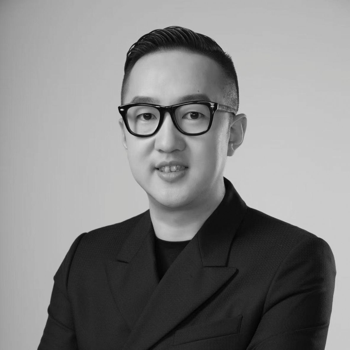 Black and white portrait of a smiling man in traditional clothing.
