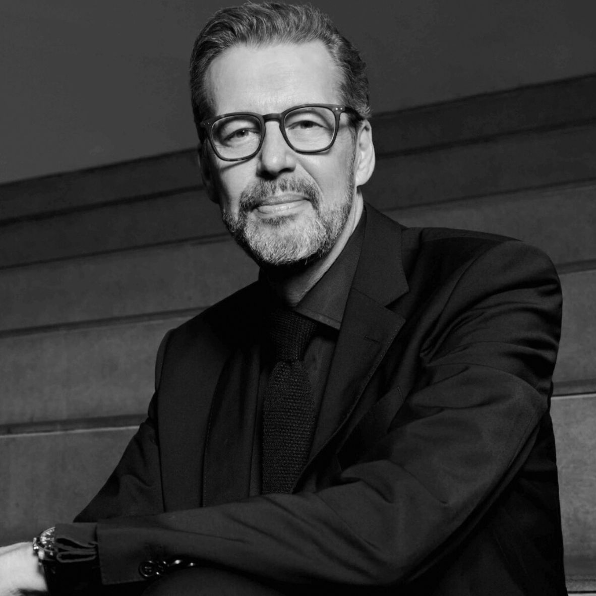 Black and white portrait of a smiling man in traditional clothing.