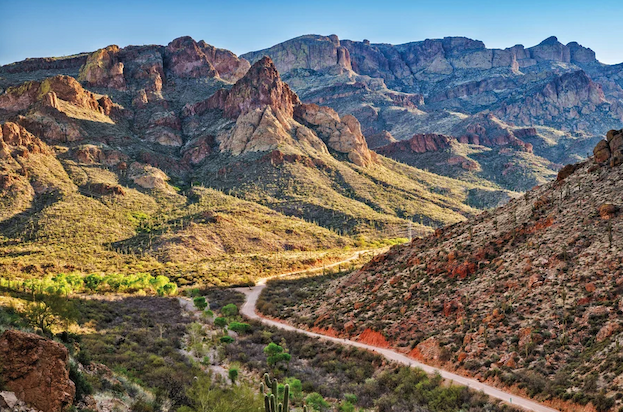 View east in Tonto National Forest from Fish Creek Hill vicinity, over the Apache trail and a valley, with dramatic rocky features peppered with cacti and other vegetation.