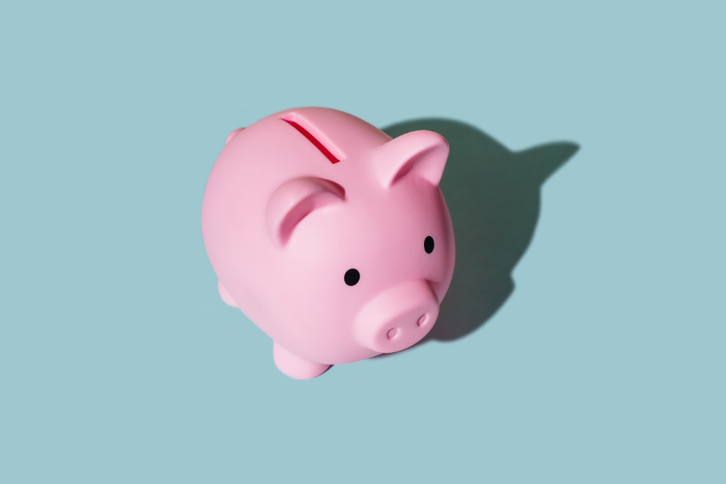 simple photo or illustration of a pink piggy bank against a blue background