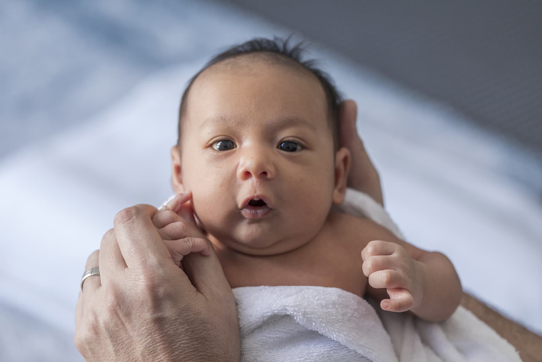 Close up photo of a one week old baby boy with dark hair and eyes open