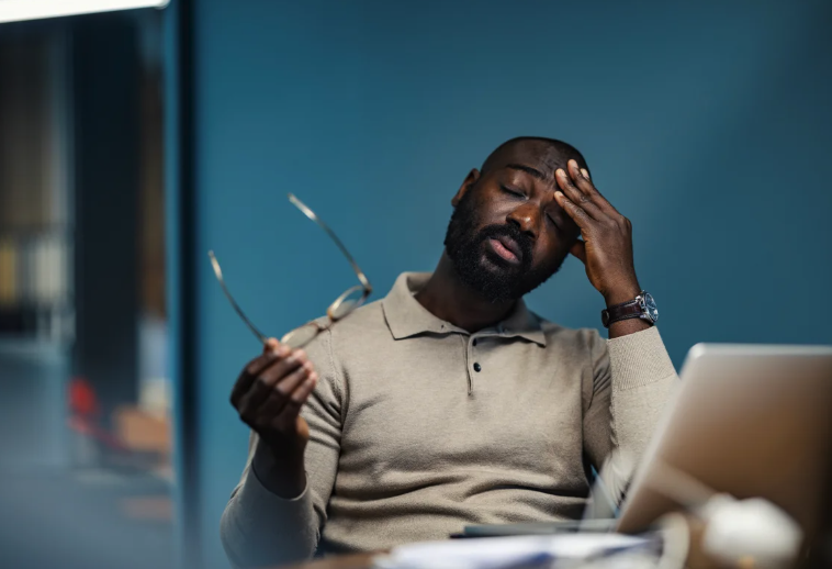 A man with his eyes closed rests his head in his hand, holds his glasses with his other hand, and in general looks exhausted.