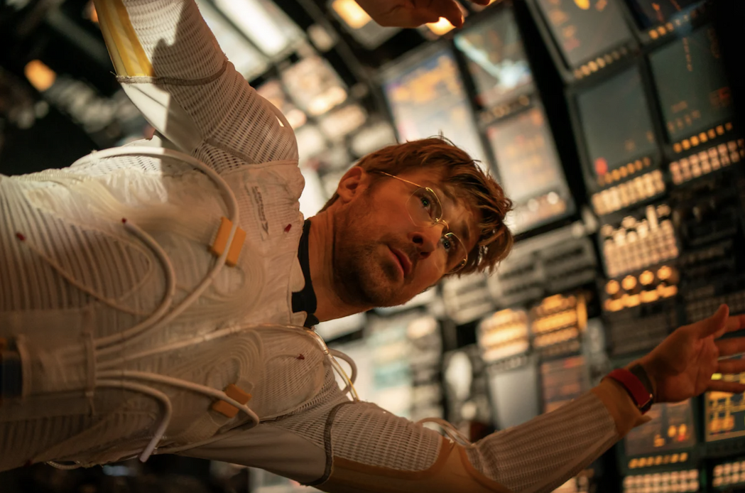 A photo of Ryan Gosling, a mean wearing glasses and a spacesuit, floating in a spacecraft.