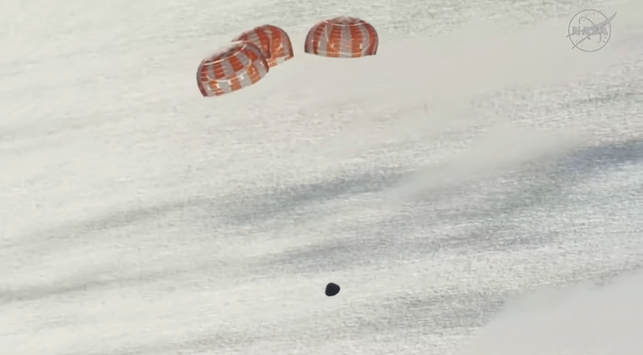 Three parachutes above the Orion capsule over the ocean.