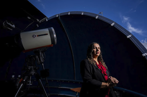 Desireé Cotto-Figueora at a space observatory, sitting next to a telescope, in Puerto Rico.