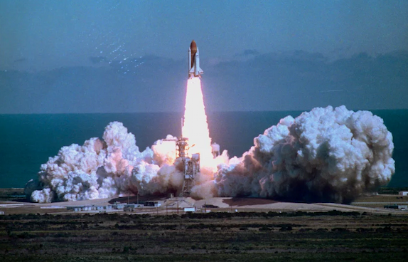 The shuttle Challenger rises on a pillar of flame