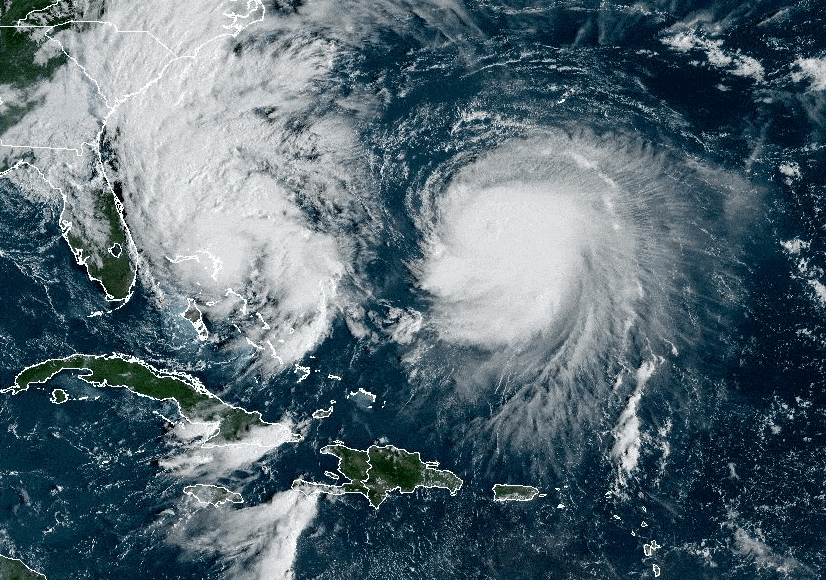 A satellite image shows a large white hurricane (Humberto) next to Tropical Storm Imelda just southeast of Florida and north of the Caribbean islands.
