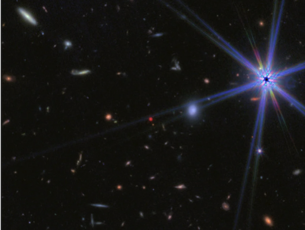 A small red dot at the center of a blurry image of the cosmos.