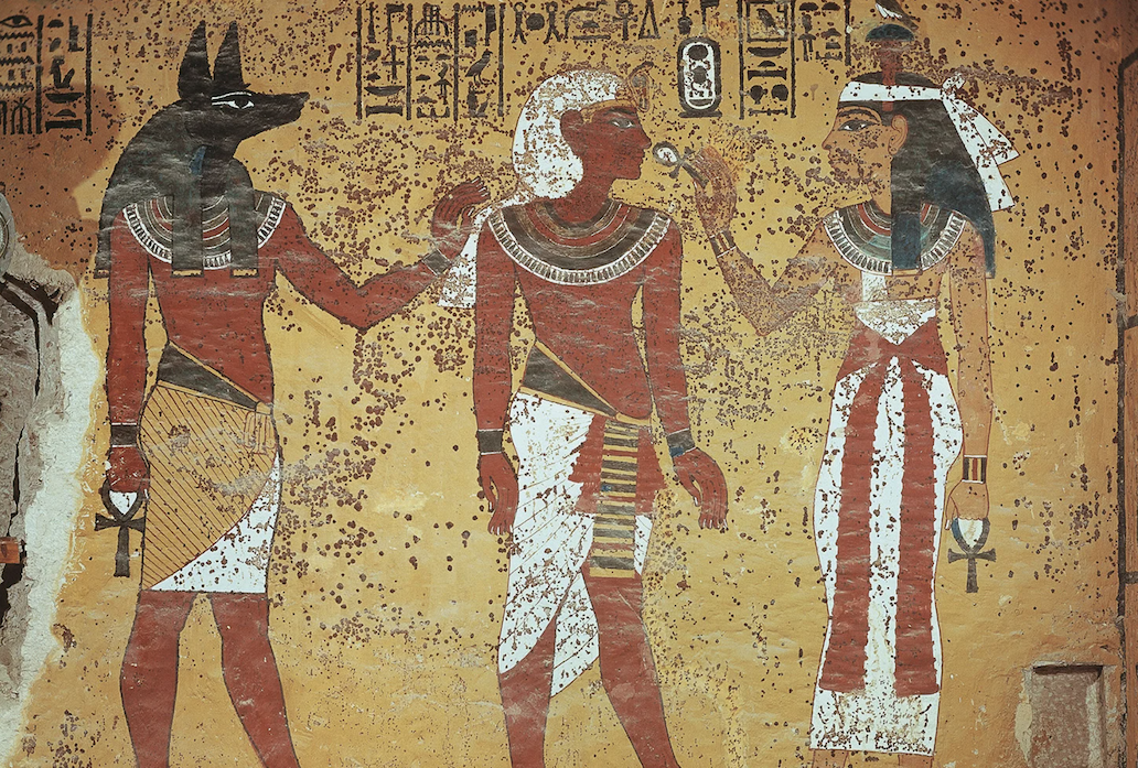 An image of a wall painted with three ancient Egyptian figures. It's covered in brown dots discoloring the painting