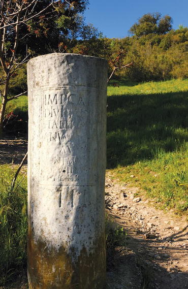 A stone cylinder bears an engraved inscription.