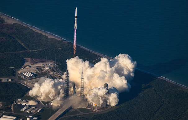 A space shuttle launches above an outburst of smoke