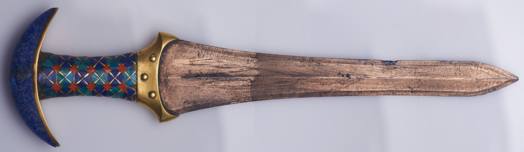 A wooden dagger with a half-moon-shaped handle, embellished with multicolored geometric designs.