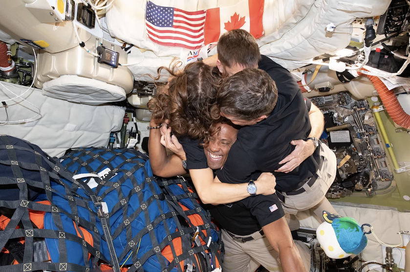 The four astronauts of the Artemis II crew share a group hug inside the capsule