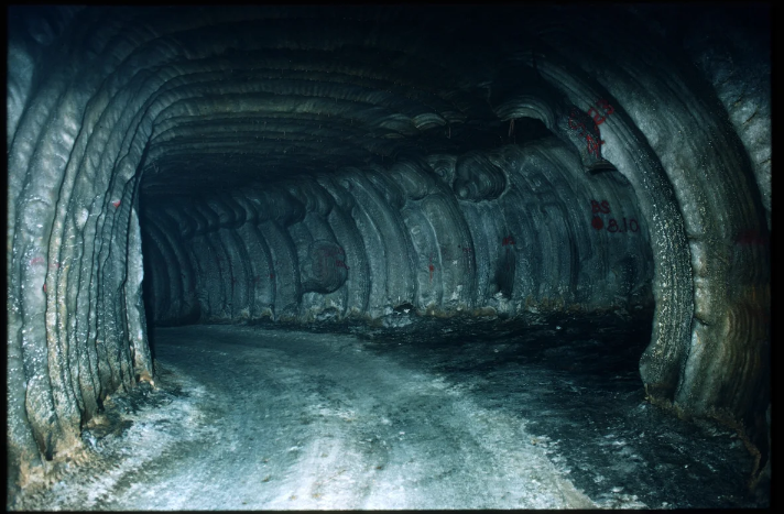 A dark tunnel through white, gray and brown material