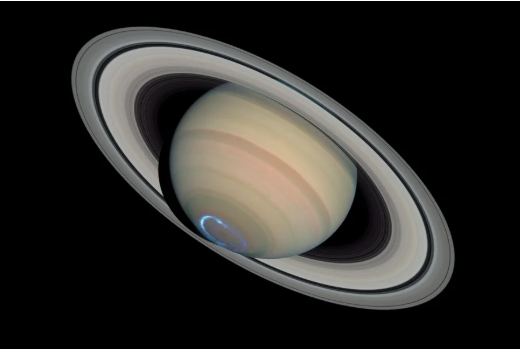 image of Saturn, with rings, shown at an angle, with its aurora, a silver-blue ring, at its base. Hubble space telescope ultraviolet-light observations of an aurora are superposed on a visible-light image of the planet.