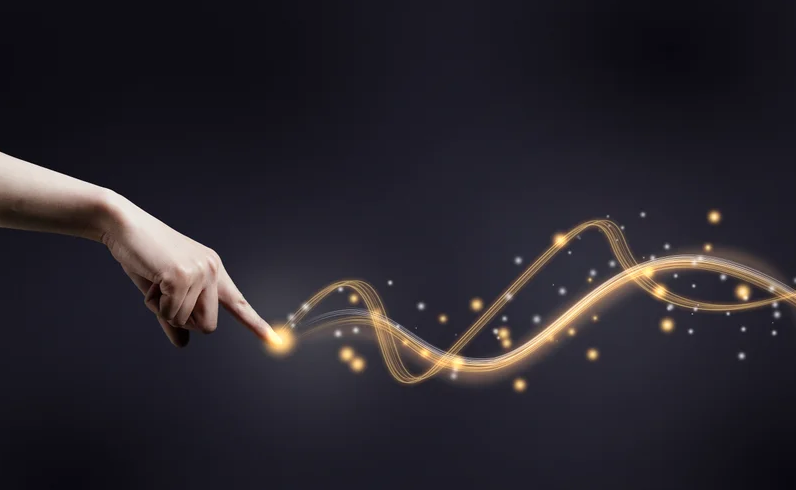 A human hand pointing its index finger at a glowing trail of waves against a dark background