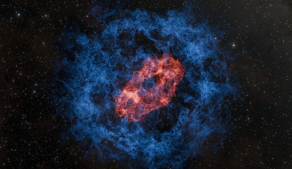 A cosmic explosion, with red gas and dust in a donut shape, surrounded by a ring of blue dust.