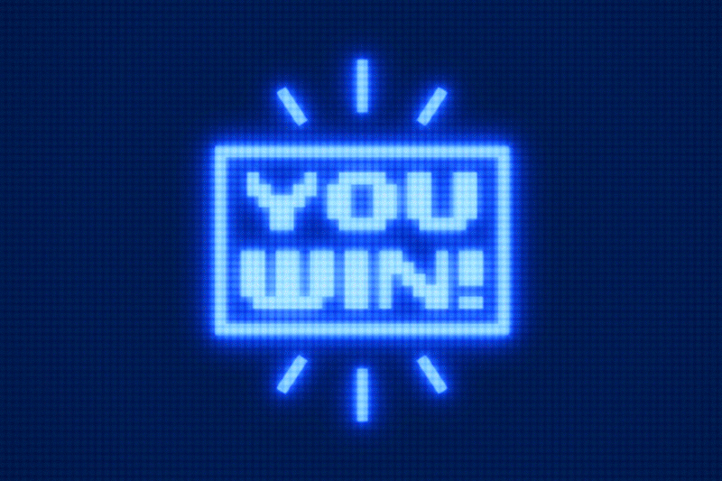 Animation of a retro video game arcade screen with text reading, "YOU LOSE, " flashing twice, followed by a glitch and the text changing to read, "YOU WIN!"