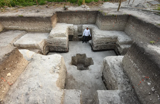 A series of cross shaped pits that are smaller as they get deeper. A person stands near the top of the photo giving a sense of scale