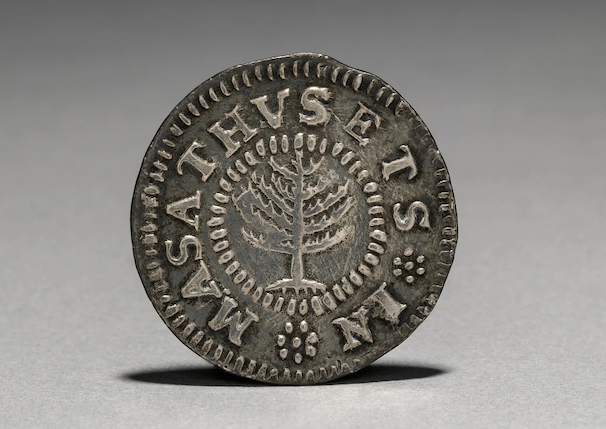 An old coin that reads "In Masathvsets" with a pine tree at the center