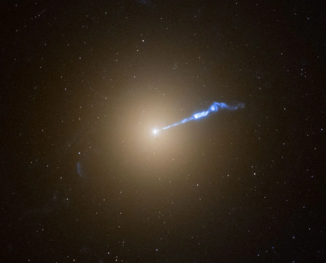 Photo of a bright light source against a dark star field, with a thin, blue-white jet spewing from its center and heading to the right.