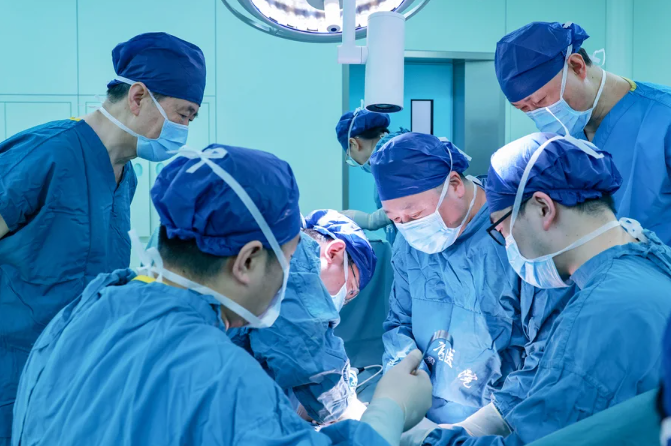 photo of a group of masked and gowned doctors and medical staff performing a kidney xenotransplant surgery in operating room at Xijing Hospital of the Air Force Medical University in Xi'an, China