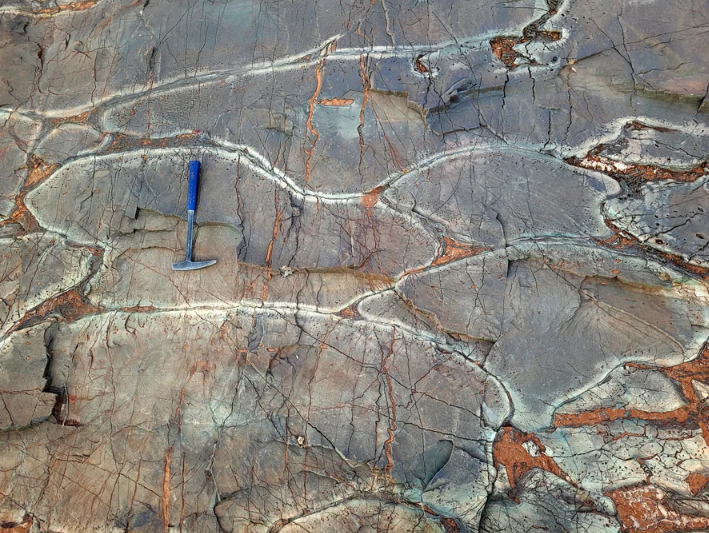 Photograph of a wavy, blobby form of rock with cracks across it.