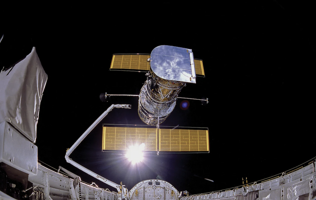 The Hubble Space Telescope with mirrors and solar panels floating in space.