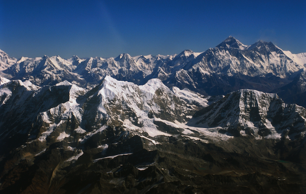 A snow covered mountain range with blue skies above.