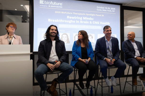 Photo of a panel of people seated in chairs in front of a projection screen